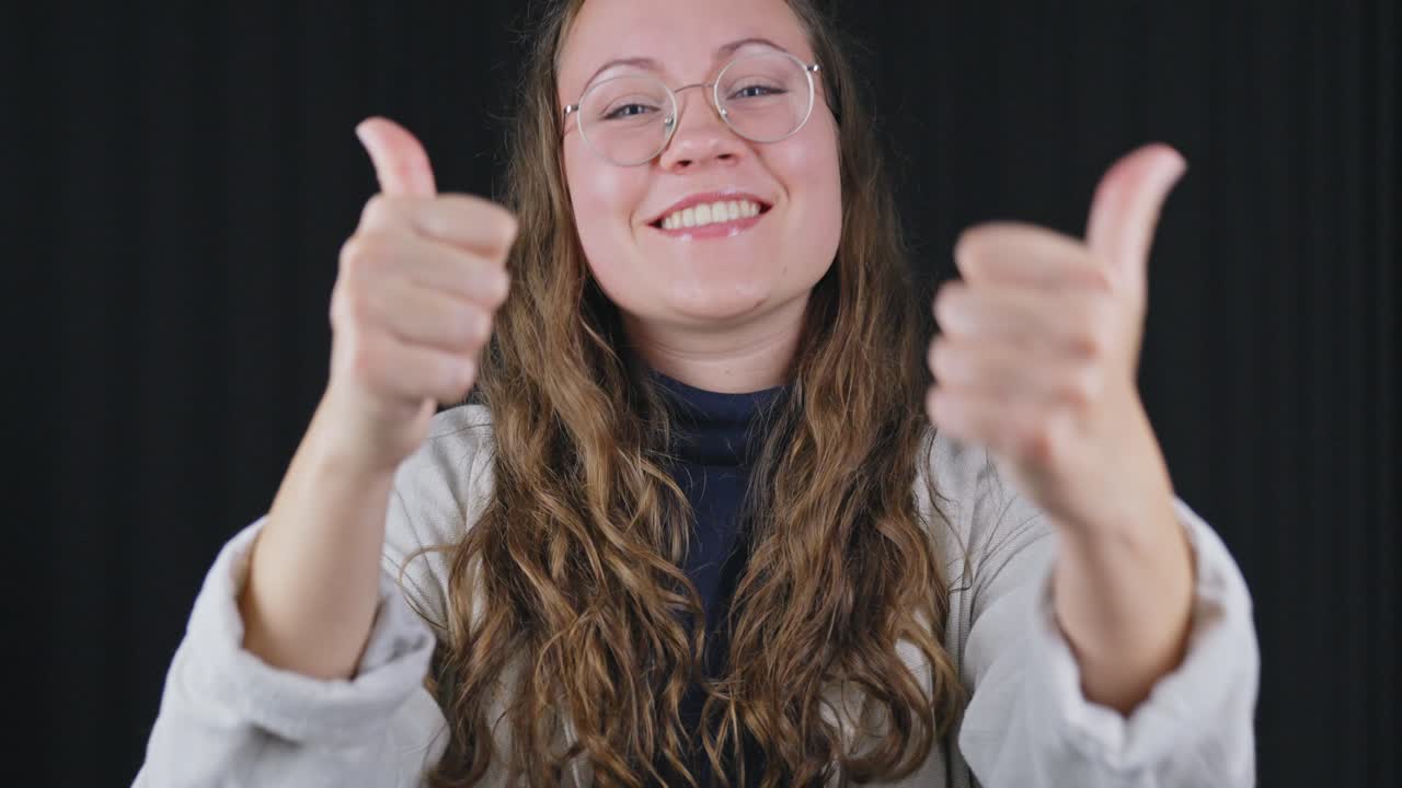 disparo estable, mirando a la cámara, mujer emocionada mostrando los pulgares hacia arriba