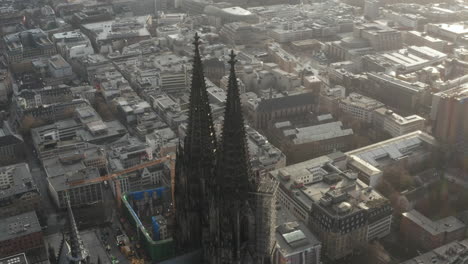 Fly-around-top-of-church-towers.-Gothic-Cologne-Cathedral-and-town-development-in-background.-Cologne,-Germany