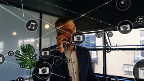network of digital icons against caucasian businessman talking on smartphone at office
