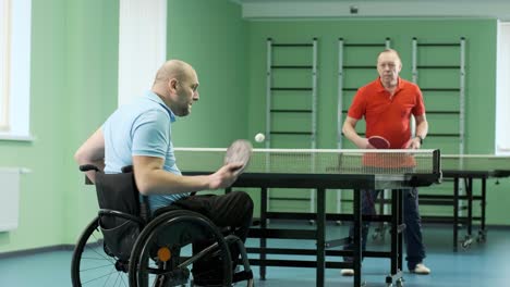 a man in a wheelchair plays ping pong. people with disabilities play table tennis. rehabilitation of the disabled. paralympic sport.