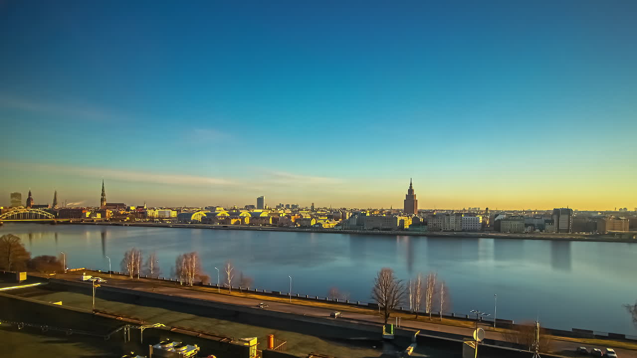 todo el día y la noche lapso de tiempo de la ciudad de riga, letonia desde el otro lado del río daugava