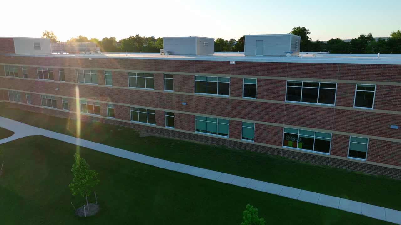 Elementary school in America during spring sunset. Aerial truck shot of brand new school. Classroom windows and tall entrance to building