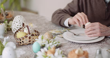 old man peeling egg on plate