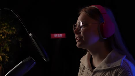 mujer cantando en un micrófono en un estudio de grabación
