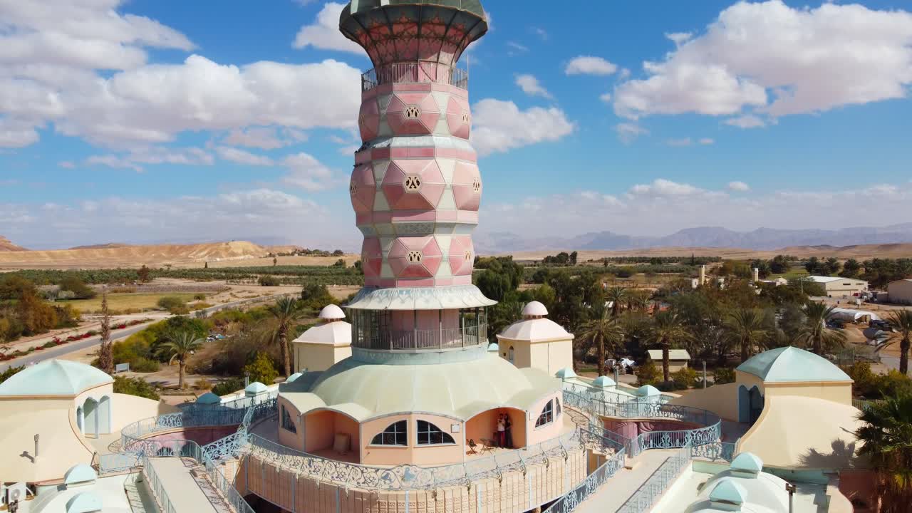 Neot Smadar Art Center building front view with cooling towers under clear blue sky surrounded by agricultural landscape with Arava desert in background, Aerial closeup, revealing shot