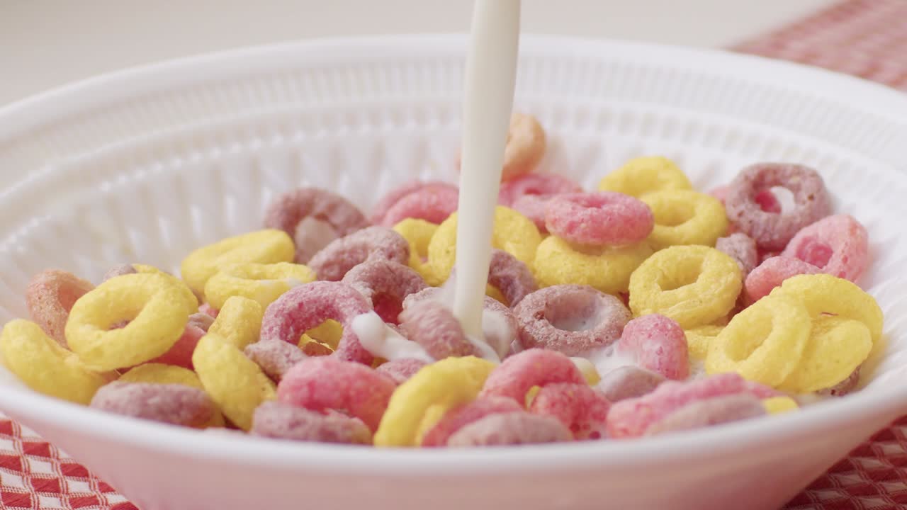 multicolored breakfast cereal in bowl with milk splash
