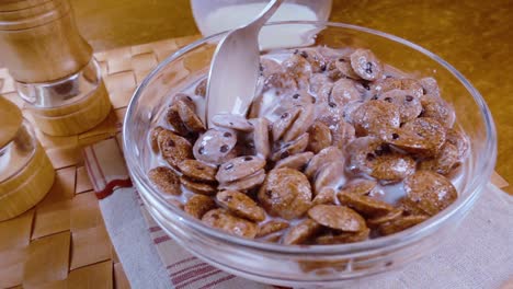 crispy chocolate flakes in a bowl for a morning delicious breakfast with milk. slow motion with rotation tracking shot.