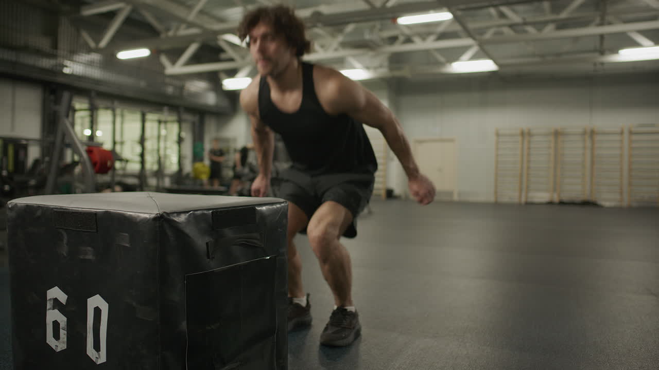 Strong Man Jumping on Plyometric Box during High Intensity Training in Gym