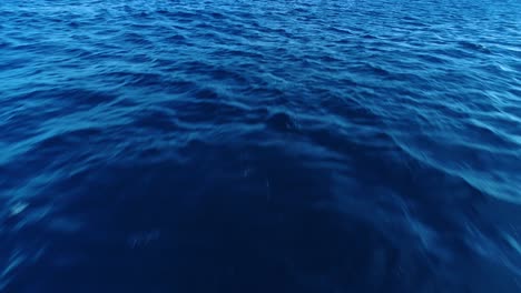 l'acqua blu profonda dell'oceano vista dalla superficie mentre le ondate e le onde soffiano attraverso la parte superiore, la consistenza dell'oceano