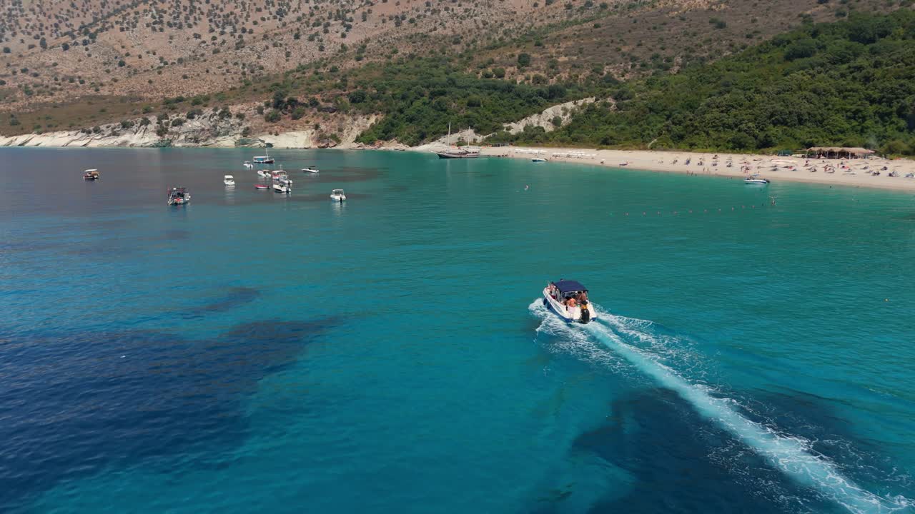 Boat speeds across clear turquoise waters near a scenic rocky coastline on a sunny day
