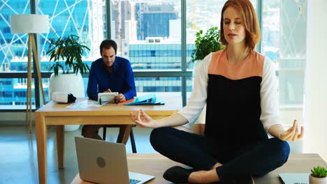 female executive meditating at her desk