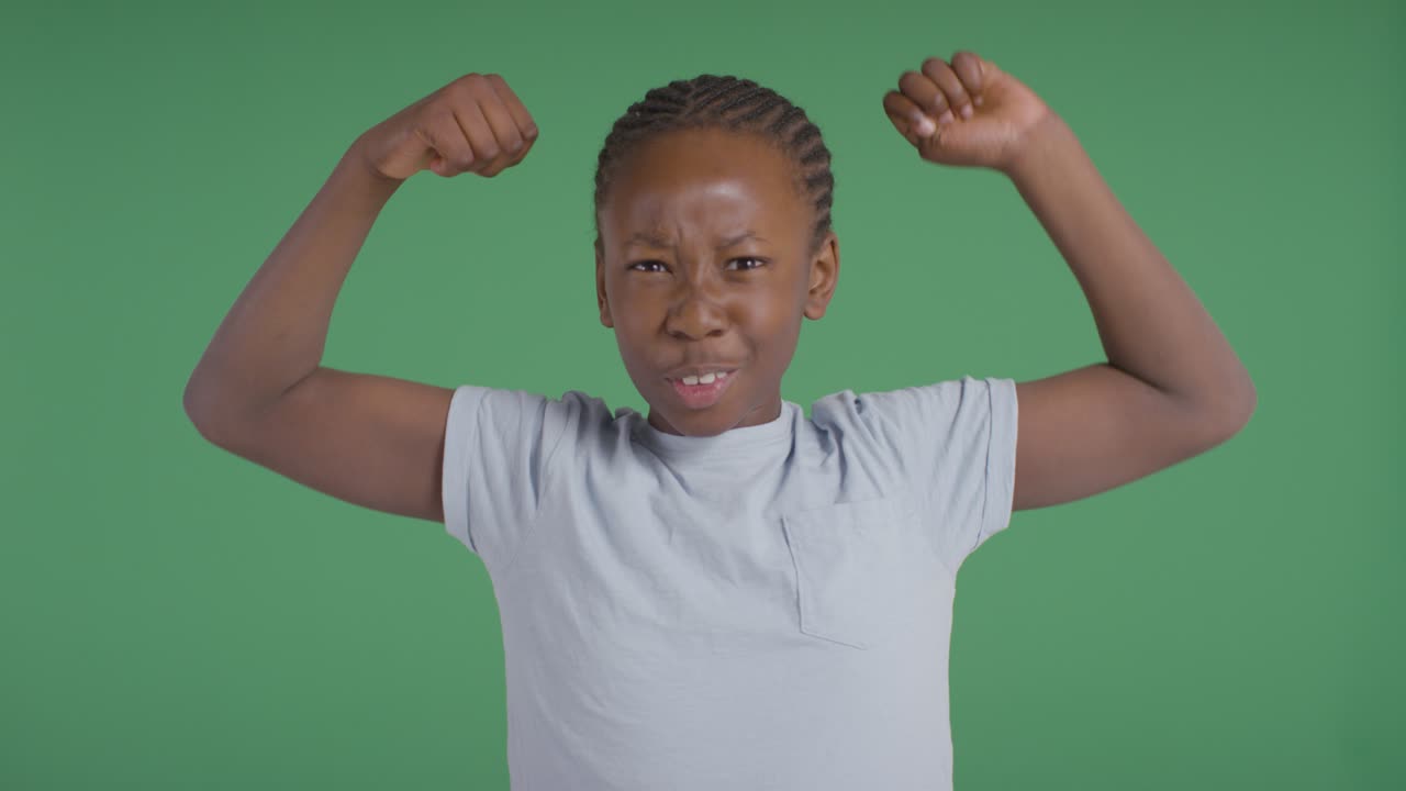 foto de estudio de un niño mostrando los músculos contra el fondo verde