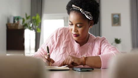 African-American-woman-writes-in-a-notebook-at-home