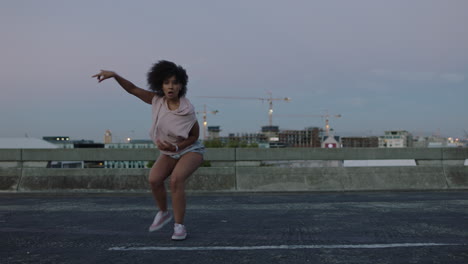 Mujer-Bailando-Bailarina-Callejera-De-Raza-Mixta-Con-Funky-Afro-Realizando-Movimientos-De-Hip-Hop-Estilo-Libre-Disfrutando-De-La-Expresión-De-Danza-Moderna-En-La-Ciudad-Al-Atardecer