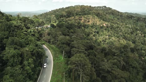 aerial drone footage captures car moving along winding highway, set against breathtaking backdrop of lush green mountainous landscape in brazil