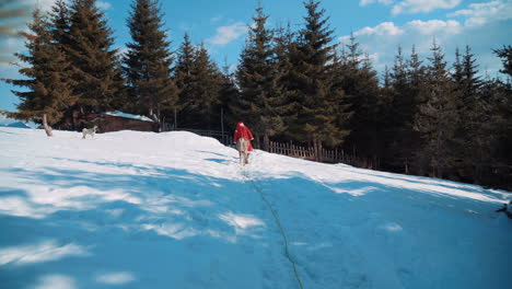 santa walks down a snowy path to a small wooden house