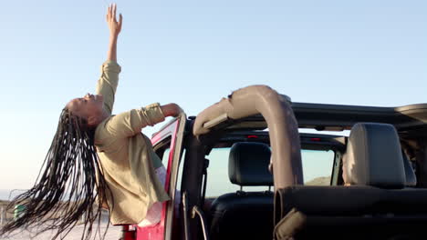 young african american woman enjoys a sunny day at the beach with her car on a road trip