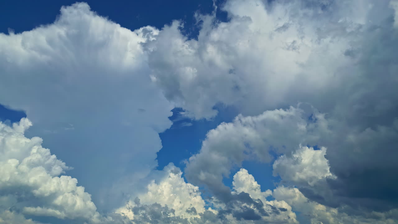 Puffy clouds drift across a deep blue sky on a sunny day creating a serene natural view