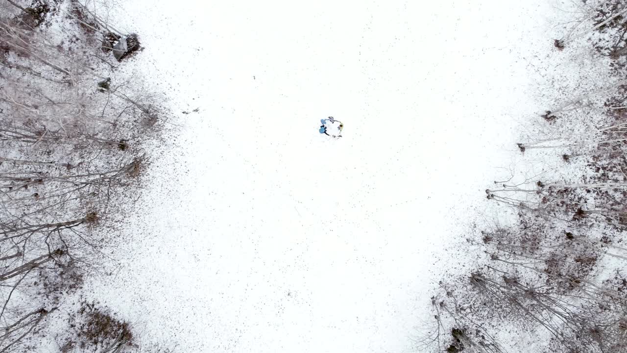 겨울의 숲에서 로지 주변에서 놀고 있는 사람들. 눈. 산의 숲 자연에서 놀이하는 가족 위에서 공중 드론 비행. 바로 아래 관점. 함께. 4k  뷰 비디오.