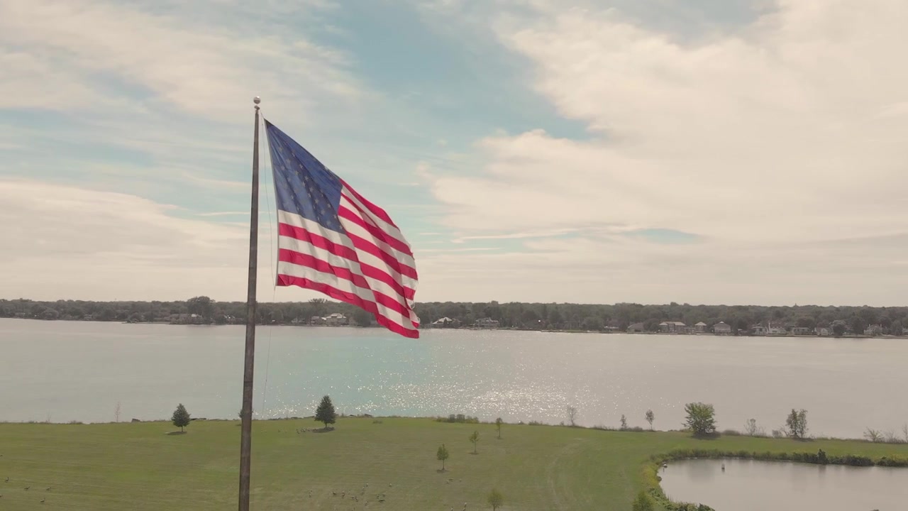 Bandiera americana che sventola nel parco con lo skyline della città e un fiume