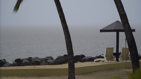 raining season at a resort with sun loungers and fixed beach umbrella, static