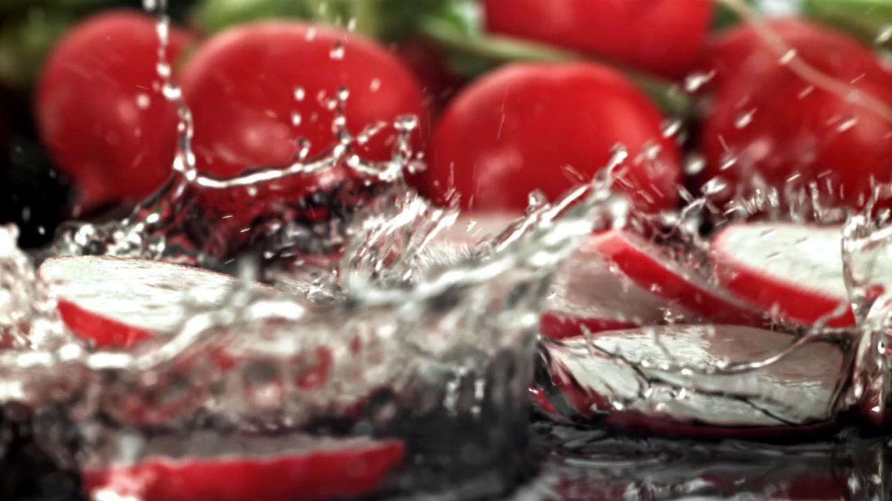 Zeitlupe von frischen Radieschenscheiben, die ins Wasser spritzen