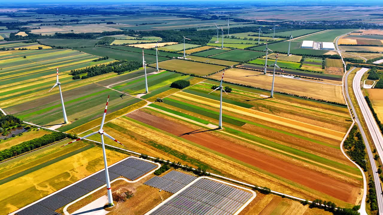 Beautiful picturesque vast countryside fields. Wind turbines and solar panels installed in the rural area. Aerial view