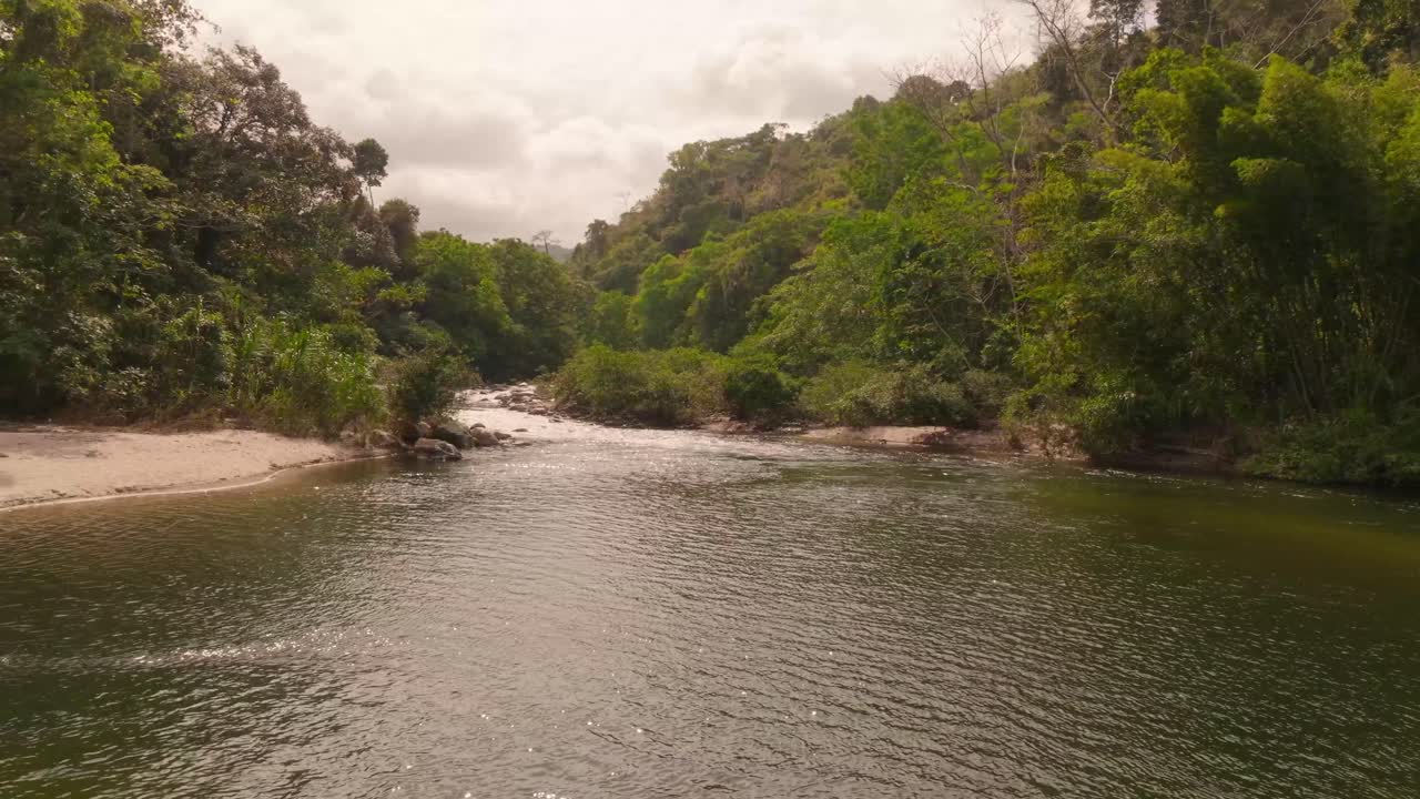 Drone shot of the river near Seydukwa indigenous village in Sierra Nevada de Santa Marta, Colombia, winding through lush tropical jungle and mountain landscape