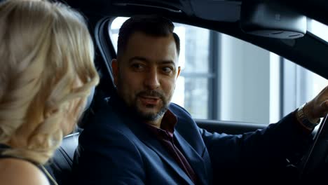 successful couple testing new car in salon