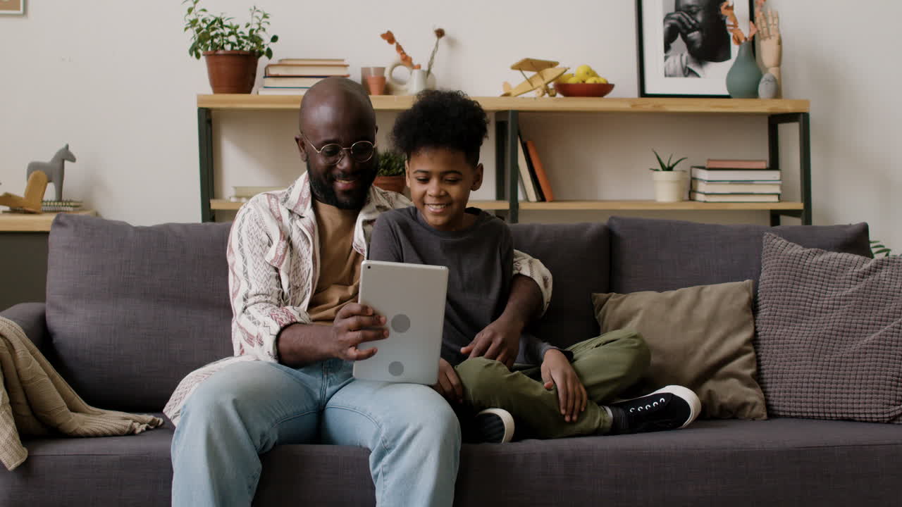 Father and son using tablet in the living room
