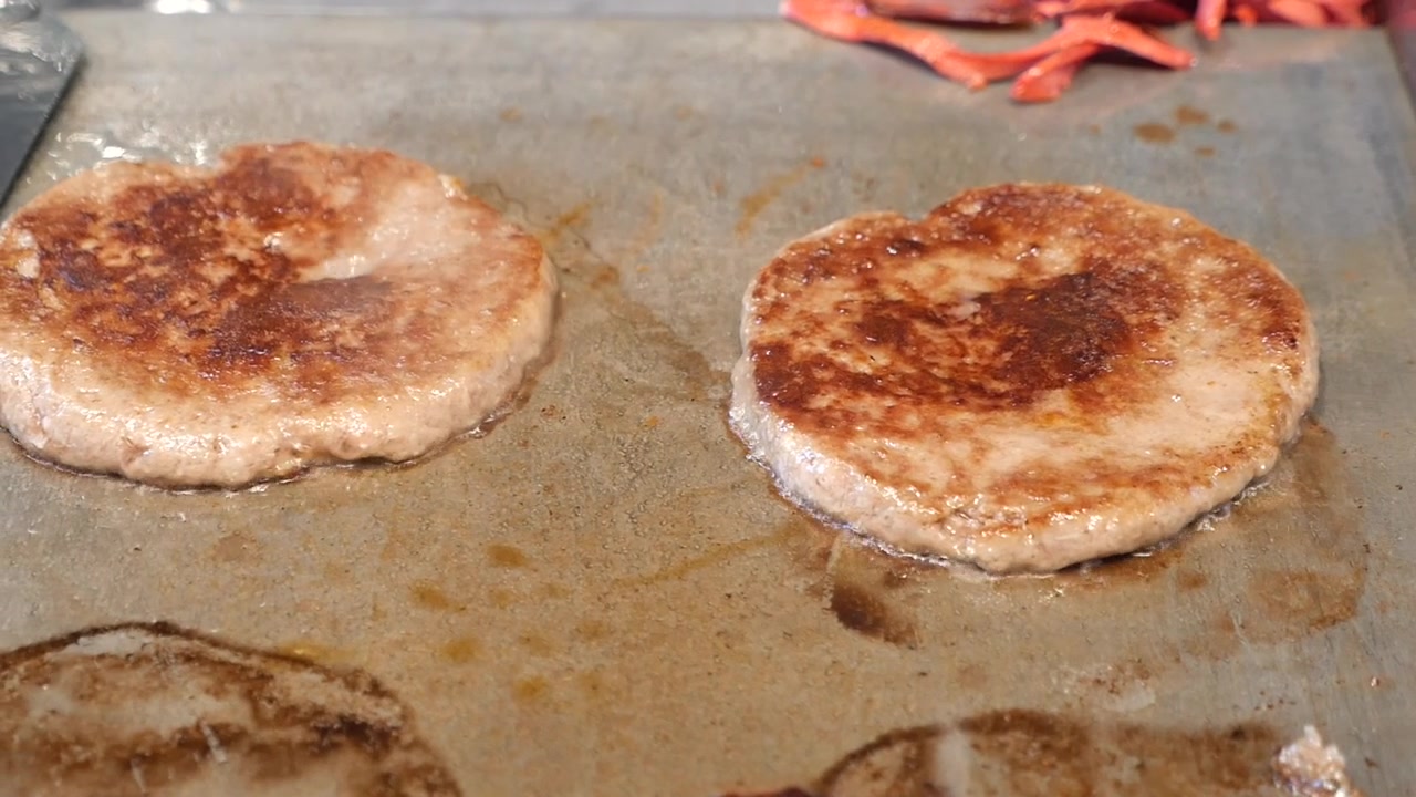 To oksekødsburgerbøffer syder på en varm stegeplade
