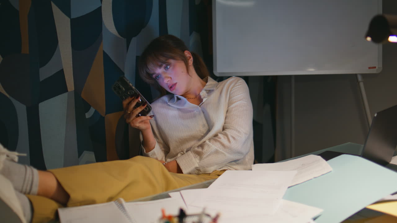 Evening boss watching smartphone at dark private cabinet. Woman resting night