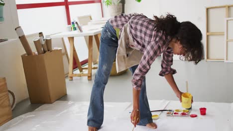 video of biracial female artist painting on floor in studio