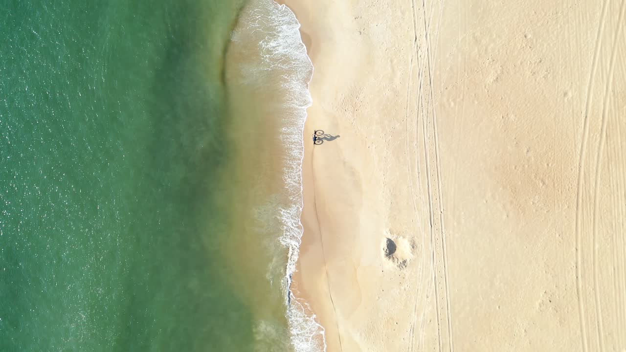 Ciclista che pedala lungo una spiaggia dorata