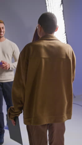 Vertical-Video-Of-Film-Crew-And-Female-Director-Congratulating-Actors-After-Performance-Shooting-Movie-In-Studio-Shot-In-Real-Time