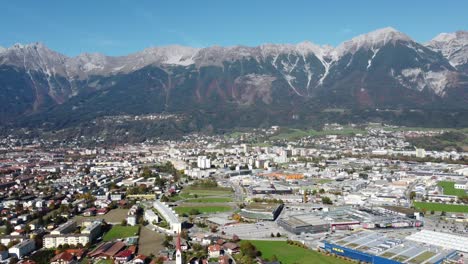 innsbruck in a panoramic vertical aerial view on a sunny day full of autumn tranquility with a green alpine forest and a blue sky and the alps in the background with its peaks in tyrol in austria