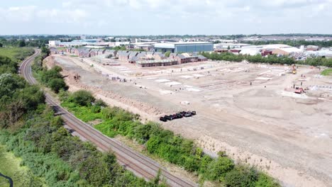 UK-town-housing-development-working-foundation-construction-site-aerial-view-slow-rising-right