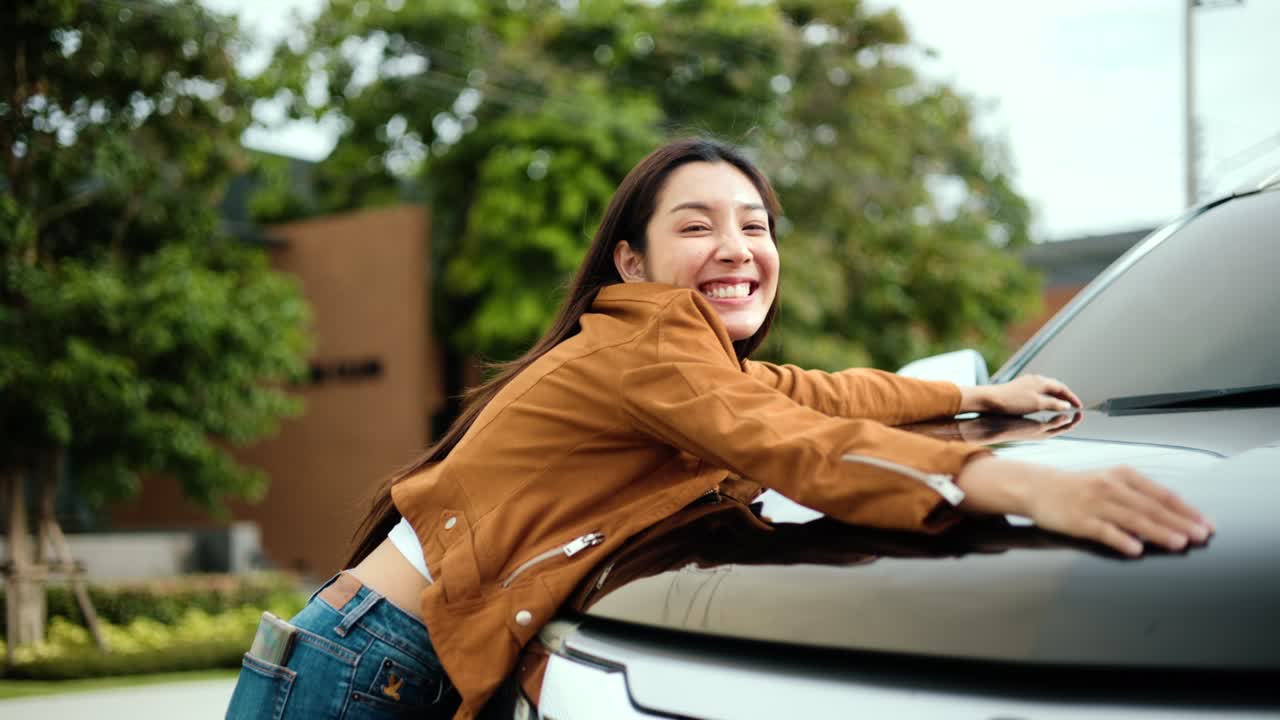 sorprendido joven asiática conseguir el coche nuevo. ella abrazó su coche y estaba muy feliz. comprar o alquilar concepto de coche.