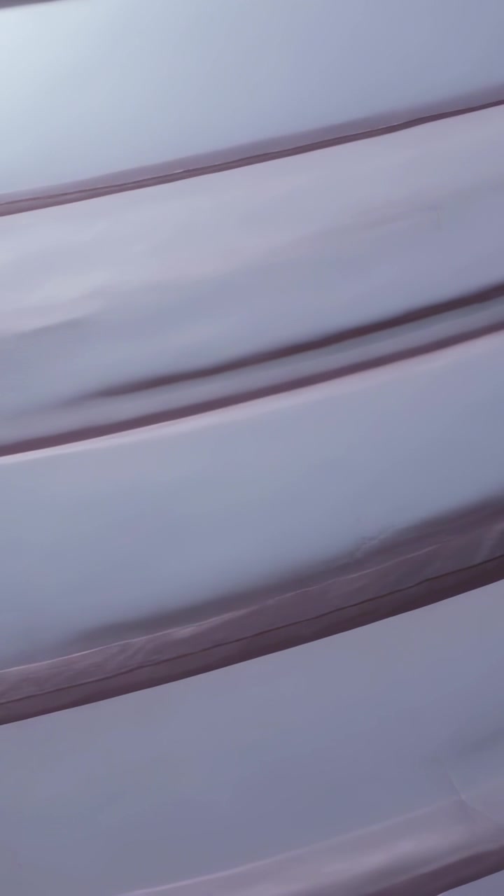 Vertical video: Shifting camera capturing pleated blind sliding in room, trim catching soft light