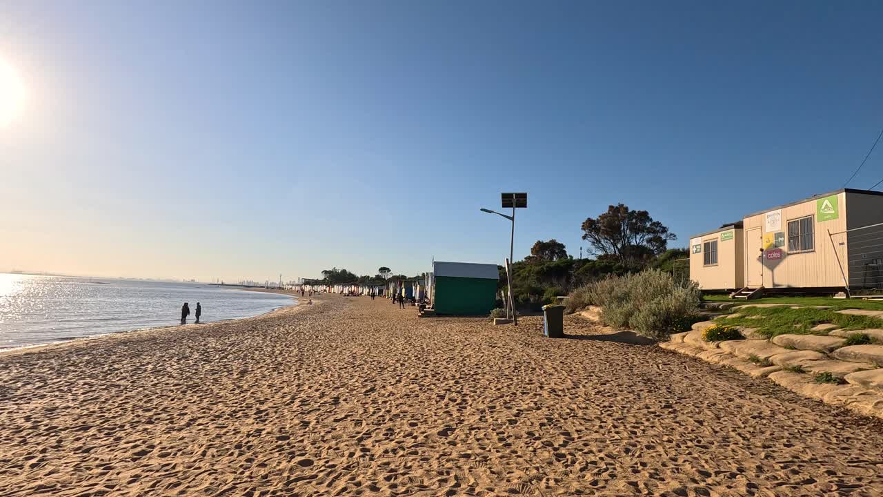 personas caminando por la playa de brighton al atardecer