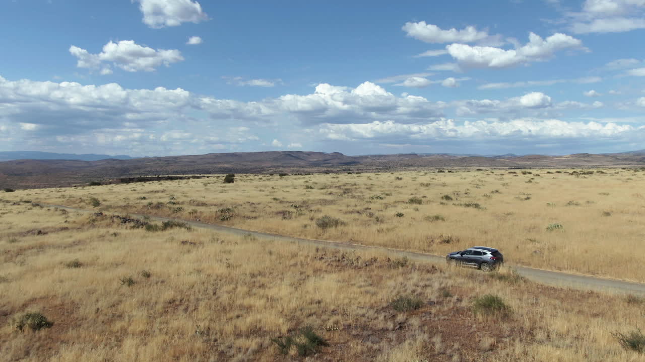 드론 은 현대 suv를 추적합니다. 프레리 풍경에서 운전하고 있습니다. 미국에서는 이 좋은 날입니다.