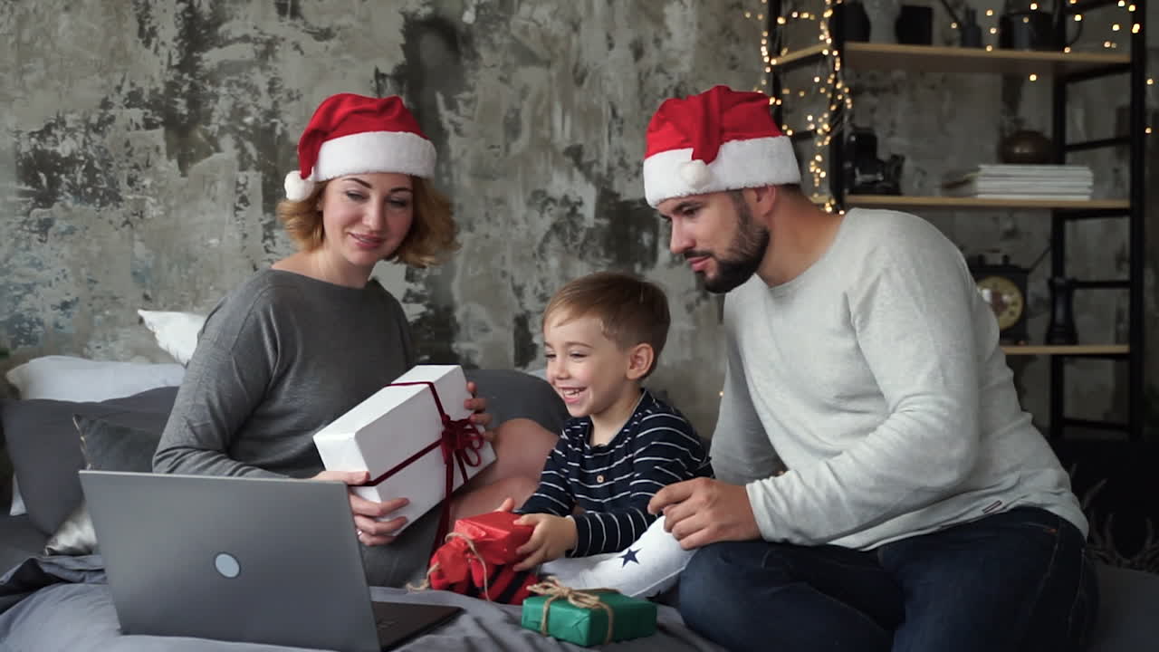 madre, padre e hijo pequeño haciendo videollamadas con su familia mostrando sus regalos de navidad