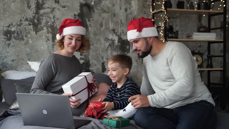 madre, padre e hijo pequeño haciendo videollamadas con su familia mostrando sus regalos de navidad