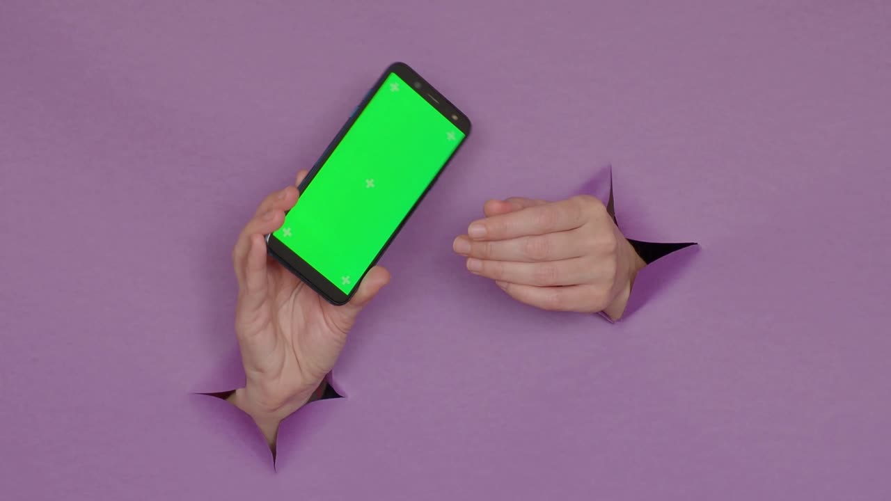 teléfono con una pantalla verde en las manos, sobre un fondo púrpura