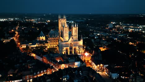 aerial drone video captures the renowned lincoln cathedral in lincolnshire, uk, at dusk, showcasing its majestic gothic architecture with illumination