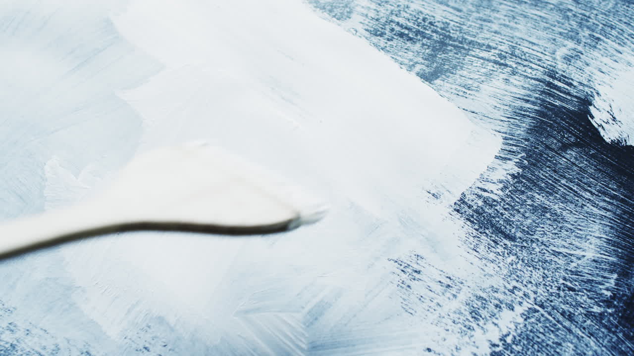 con el pincel en la mano y pintando rayas con pintura blanca sobre fondo negro, cámara lenta