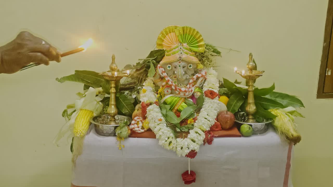 Persona indiana che accende bastoncini di agarbatti davanti alla statua di Lord Ganesh a casa. Scatto interno, stabile, 4K