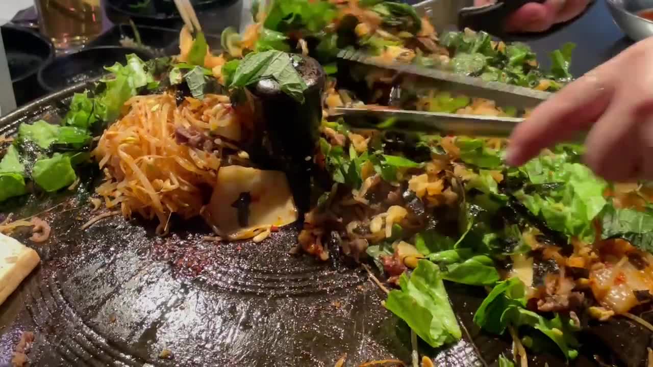 한국식 바베큐, 여성 서버가 뜨거운 주철 프라이팬 위에 김치 볶음밥을 만들고 있습니다.