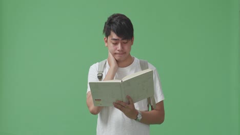 그린 스크린 스튜디오에서 책을 읽는 아시아 남성 학생을 시도했습니다.