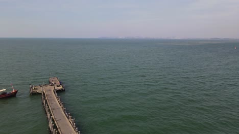 Imágenes-Aéreas-Deslizándose-Hacia-La-Derecha-Que-Revelan-Este-Barco-De-Pesca-Rojo-Y-El-Muelle-De-Pesca-De-Pattaya,-Pattaya,-Tailandia